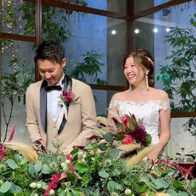 ラペルが黒いベージュのタキシードを着た新郎とドレス姿の新婦