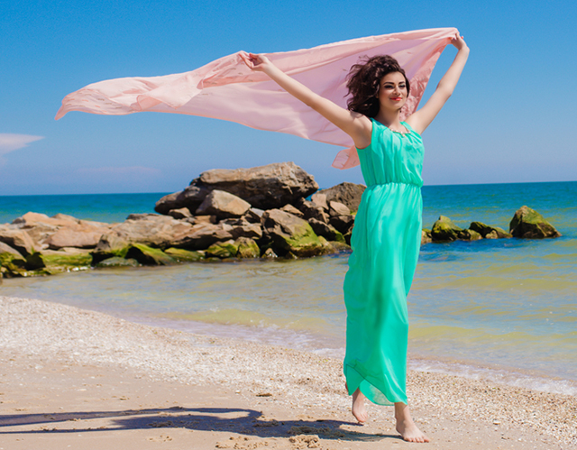 ロング丈のサマーワンピースを着て海辺を歩く女性