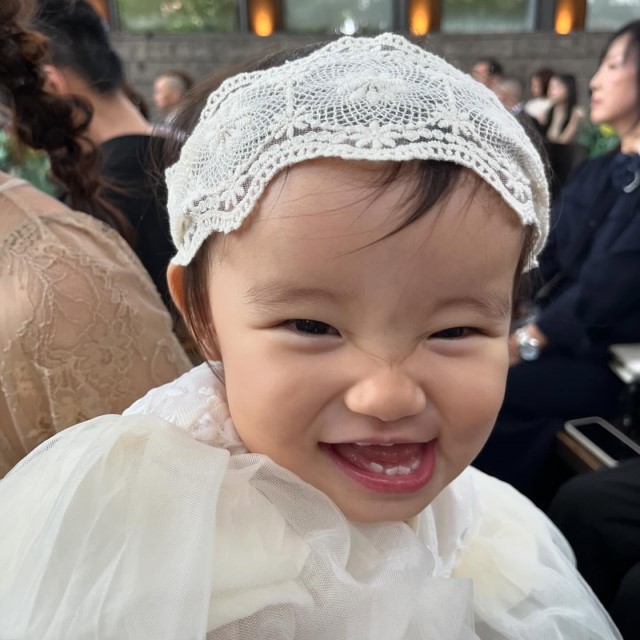 頭に白いレースのヘアバンドを巻いた赤ちゃん