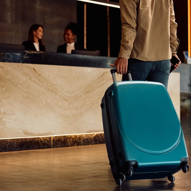 クロークにスーツケースを持っていく男性