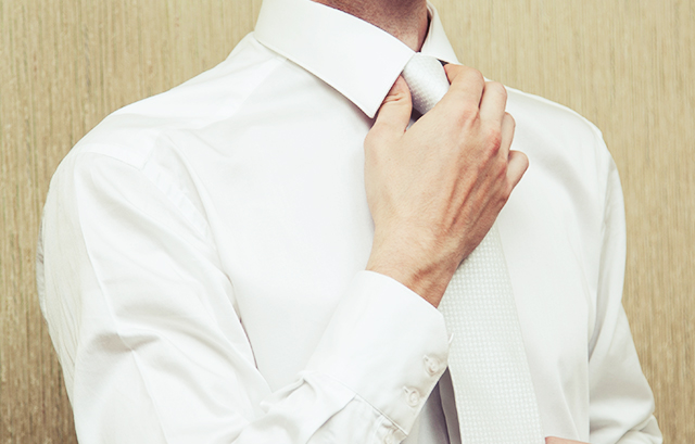 白いネクタイを結ぶ男性