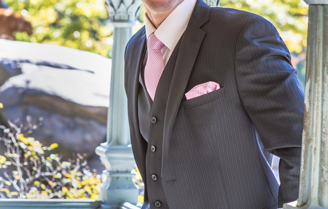 グレーのスーツにピンクのネクタイとポケットチーフ