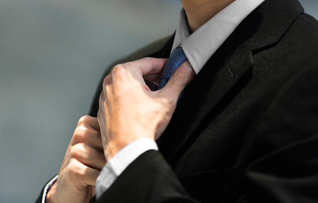ネクタイを結ぶブラックスーツを着た男性