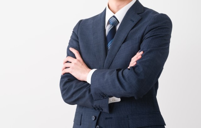 腕を組むスーツ姿の男性