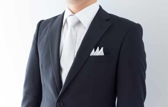 スリーピークスのポケットチーフをつけたブラックスーツの男性