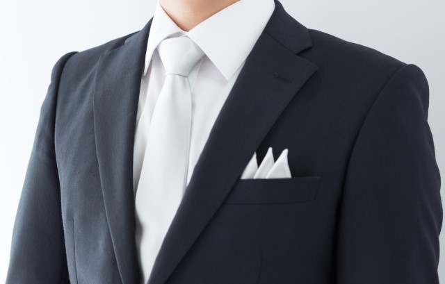 白いネクタイをつけたスーツ姿の男性
