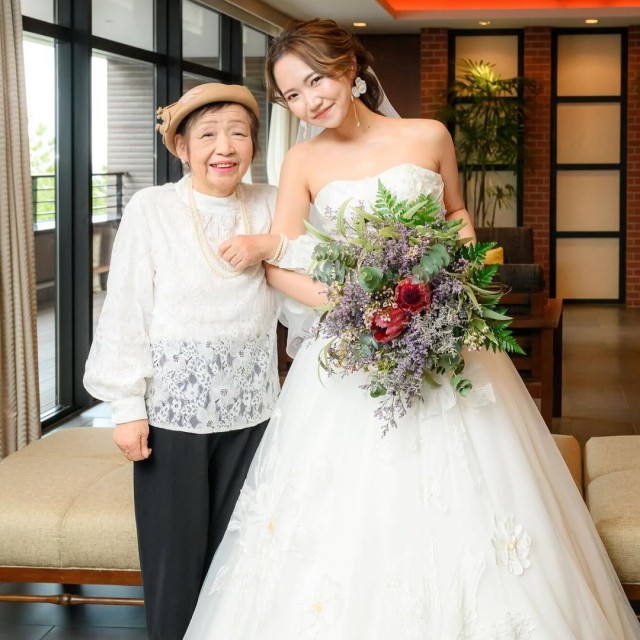 レースのトップスを着て新婦と腕を組む祖母