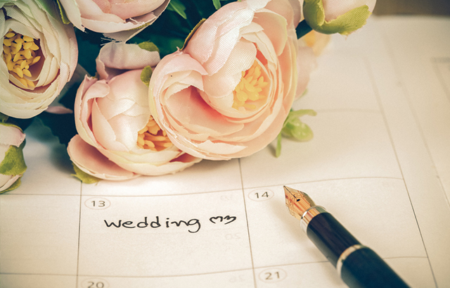 結婚式の日が書かれた手帳と造花の花束