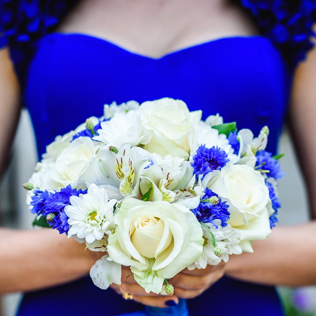 ブルーのドレスを着た女性が、ブルーの花が入ったブーケを持つ様子