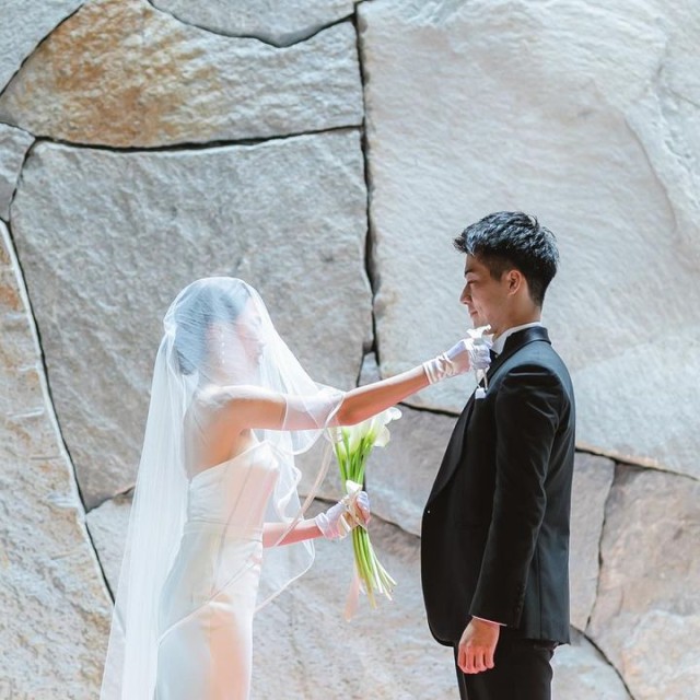 新郎の胸元にブートニアを挿す新婦