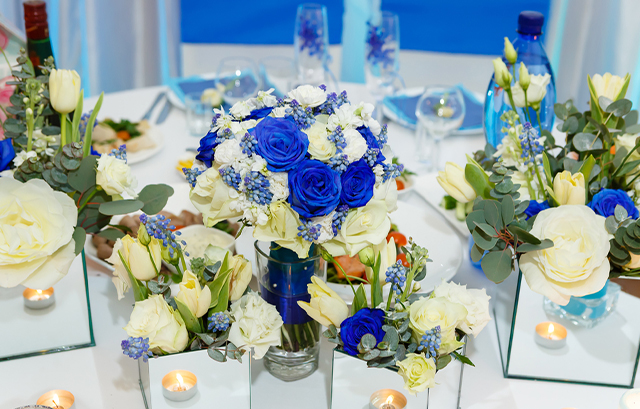 白い花やロイヤルブルーのバラが飾られたテーブル