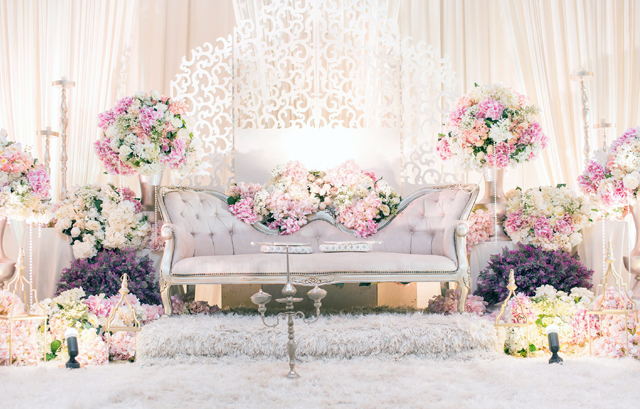 明るい色の花で白いソファを囲んだ高砂装花