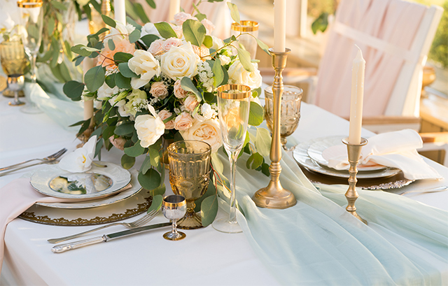 ふちがゴールドのグラスやシルバーのカトラリーが飾られたテーブル