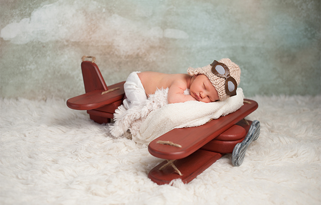おもちゃの飛行機に乗る赤ちゃん
