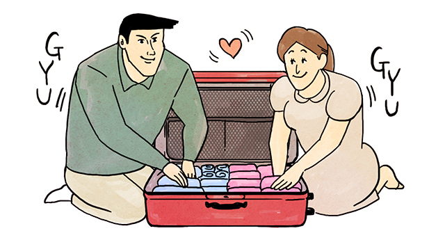 1つのスーツケースに荷物を詰める夫婦