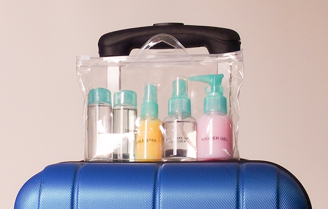 スーツケースの上に乗せた透明な袋に入れた化粧品